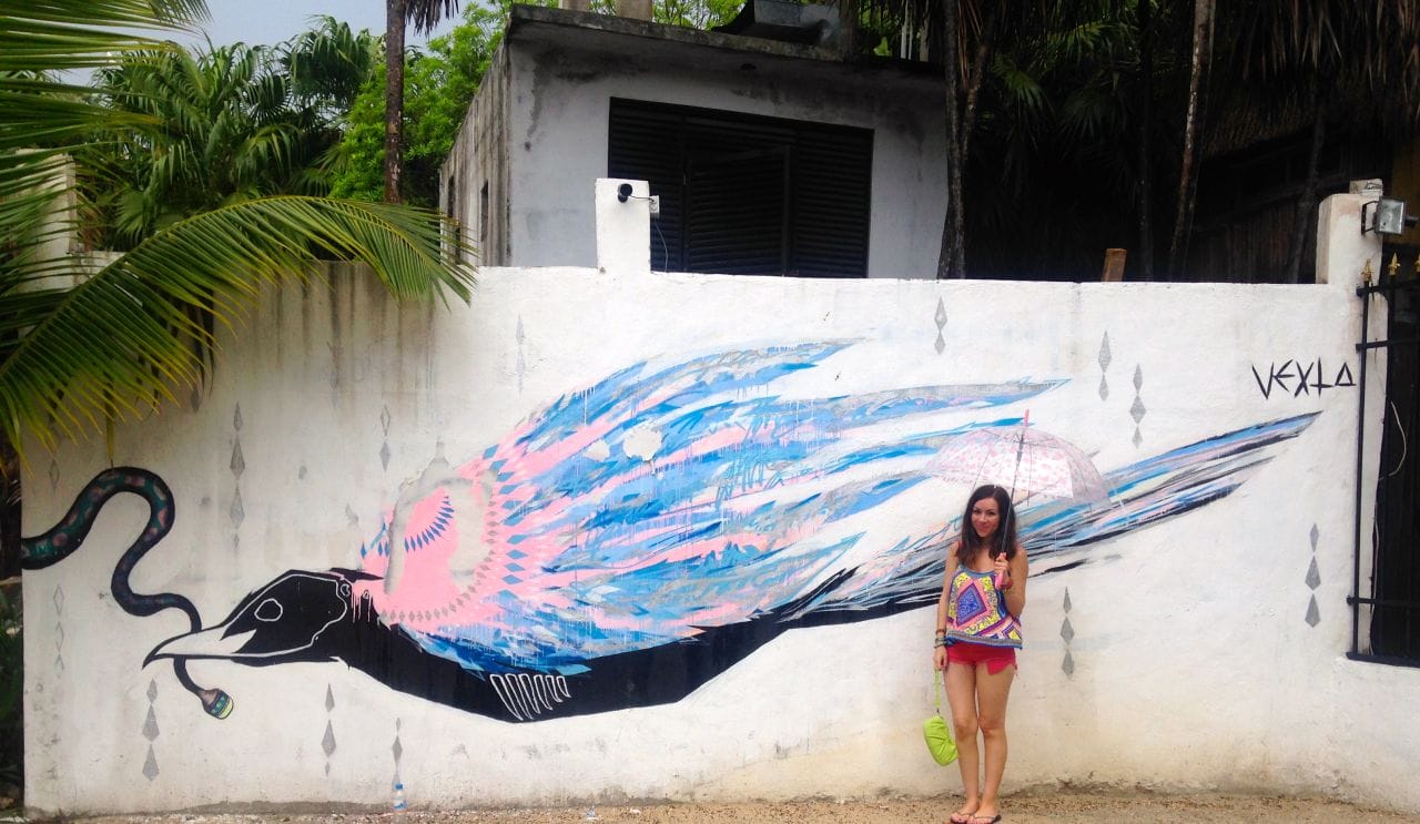 Nihan Gorkem posing in front of a bird mural in Tulum Mexico