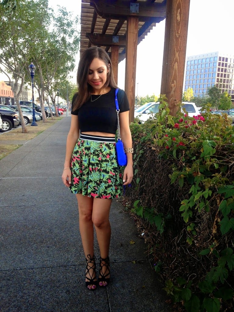 Blogger Nihan showing her fun summer outfit: a Topshop black crop top, a Topshop floral sporty mini skirt, strappy Just Fab sandals and a blue Rebecca Minkoff Mini mac purse