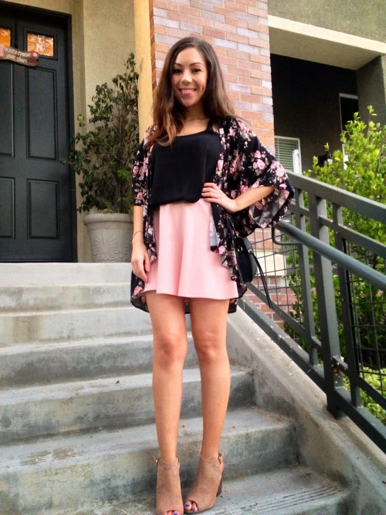 Blogger Nihan wearing a peaches and creme themed outfit: a peach skirt, black top and a floral kimono