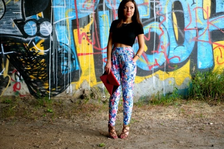 Blogger Nihan posing in front of a graffiti wall, wearing floral print harem pants, black crop top and high-heels