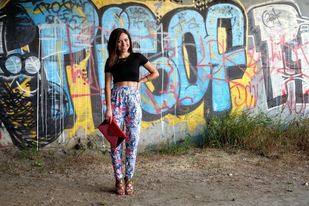 Blogger Nihan posing in front of a graffiti wall, wearing floral print harem pants, black crop top and high-heels