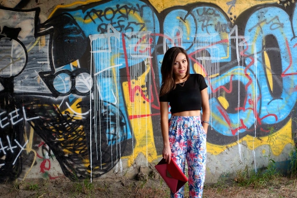 Blogger Nihan posing in front of a graffiti wall, wearing floral print harem pants, black crop top and high-heels