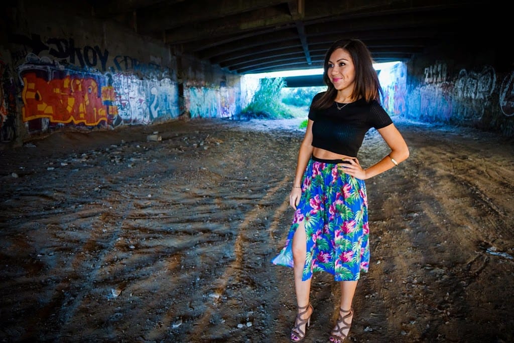 Blogger Nihan posing in front of a graffiti wall and showing her outfit: a floral midi skirt by Topshop and a black crop top