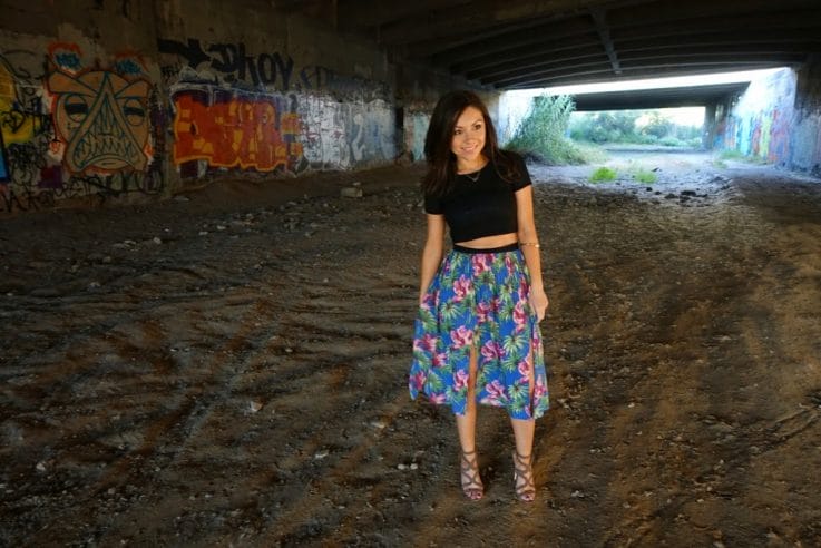 Blogger Nihan posing in front of a graffiti wall and showing her outfit: a floral midi skirt by Topshop and a black crop top