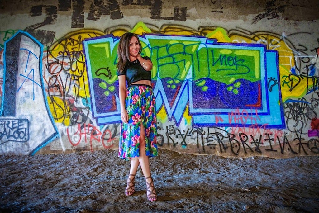 Blogger Nihan posing in front of a graffiti wall and showing her outfit: a floral midi skirt by Topshop and a black crop top