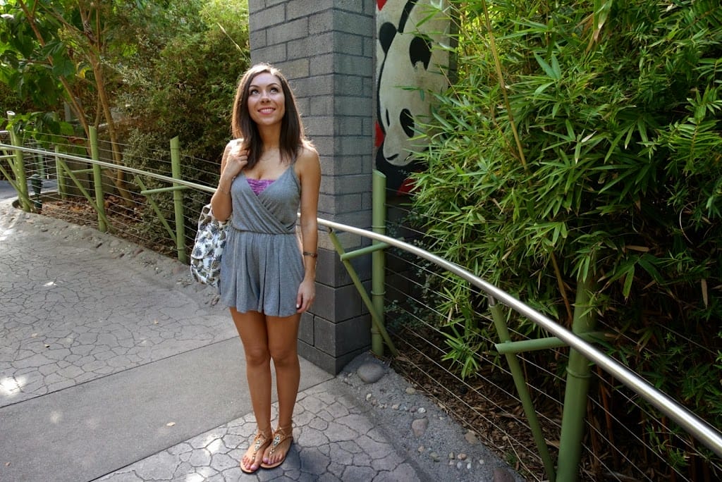 Blogger Nihan posing by the Panda Area and showing her outfit, a casual grey romper and a pineapple backpack at the San Diego Zoo