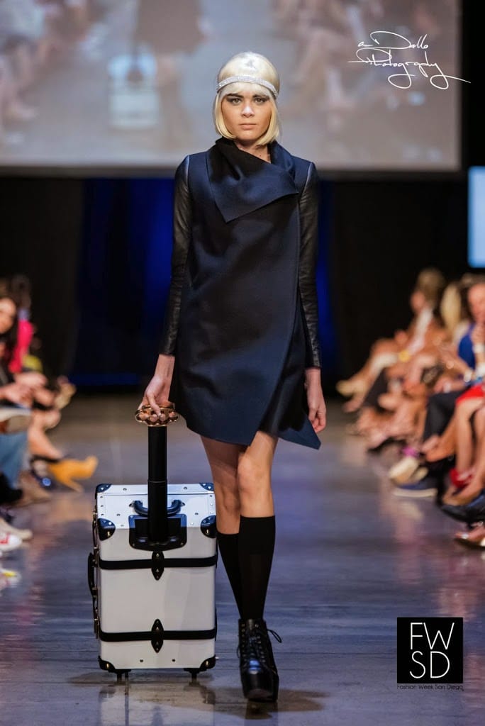 Model carrying a chic and elegant white luggage, walking down the runway
