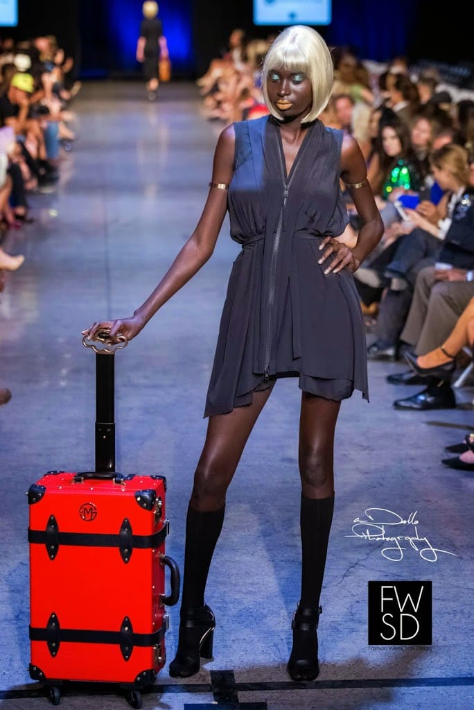 Model carrying a luggage and walking down the runway on Fashion Week San Diego 2014 Night 3