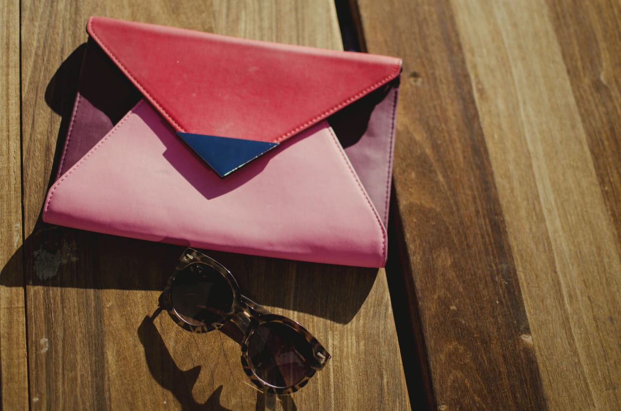 Blogger Nihan's festive, fun and trendy pink and red color block clutch and round sun glasses