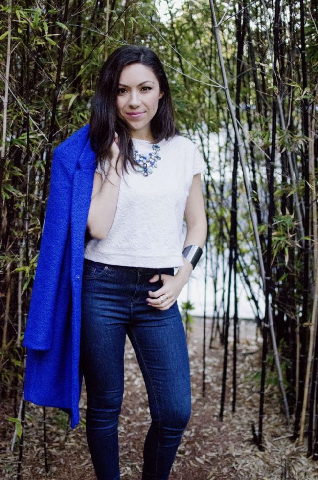 Fashion model wearing a cobalt blue coat and standing