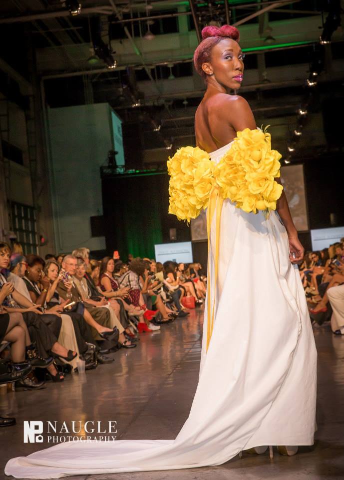 Model wearing a white gown with a yellow flower on the back by Dulce Alexandra, Duck and England