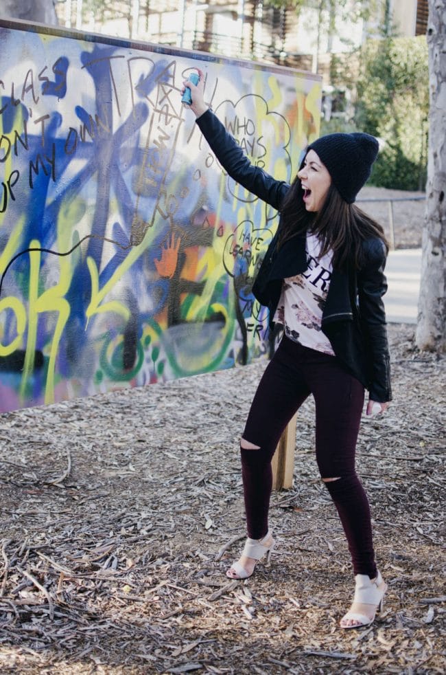 Model painting on a graffiti wall and showing her outfit