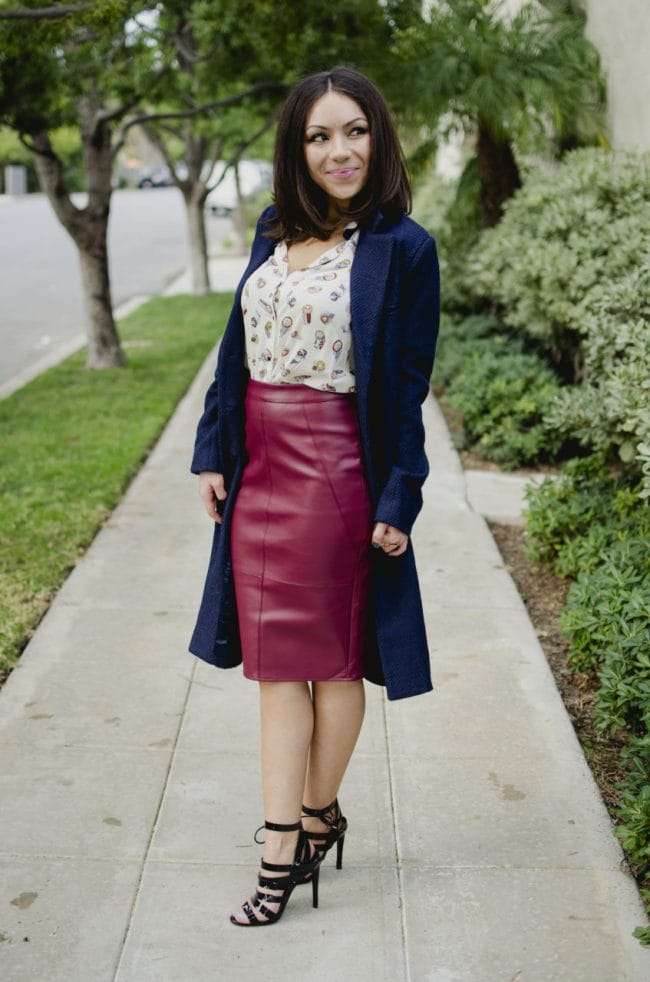 Blogger Nihan Gorkem standing and posing, wearing a Zara owly shirt, Asos leather skirt, black strappy Topshop high-heels  and Lulu's oversized navy coat and Asos color block clutch