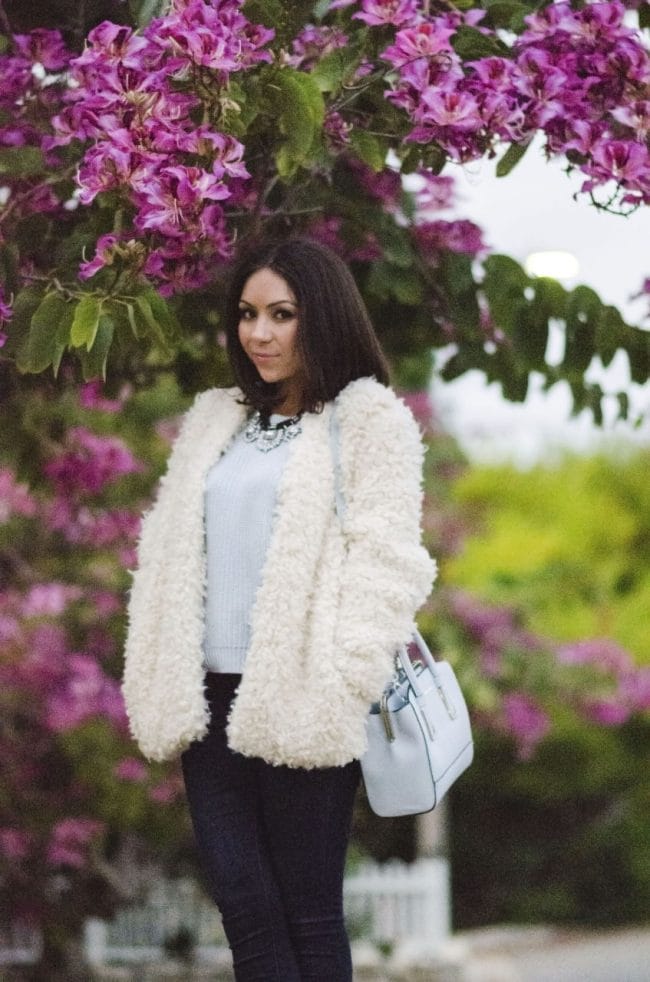 Nihan posing in front of pink gorgeous flowers, showing her outfit and fur coat
