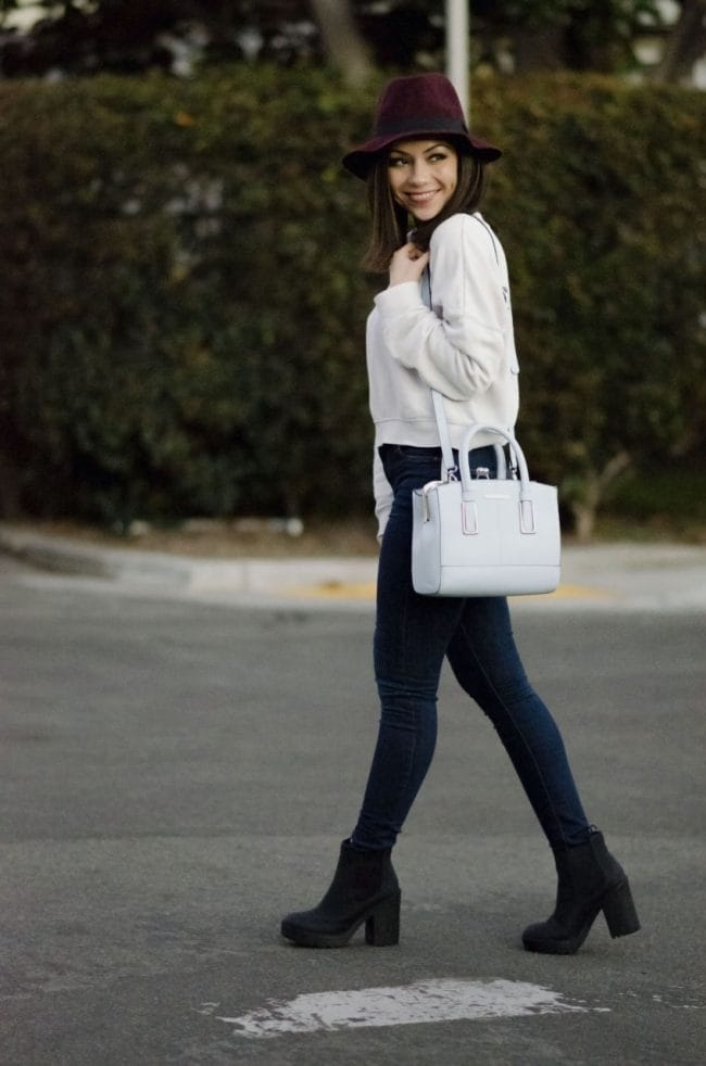 Nihan walking on the street showing her blue River island bag, Topshop jeans and a white Topshop sweathirt