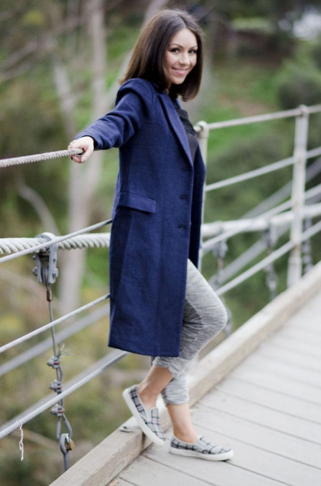Nihan wearing sweatpants, and a blue long coat at bridge