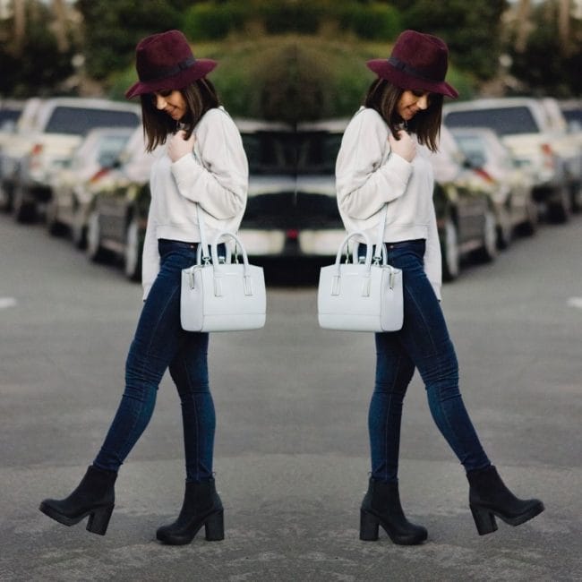 Nihan walking on the street wearing a white Topshop sweatshirt, blue jeans and a red fedora hat