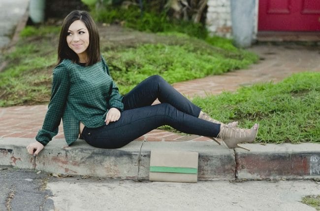 Blogger Nihan showing her green top, black pants and nude high-heels while sitting on pavement