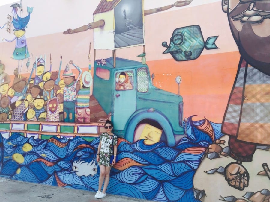 Nihan in front a Os Gemeos mural in Wynwood Walls, Miami