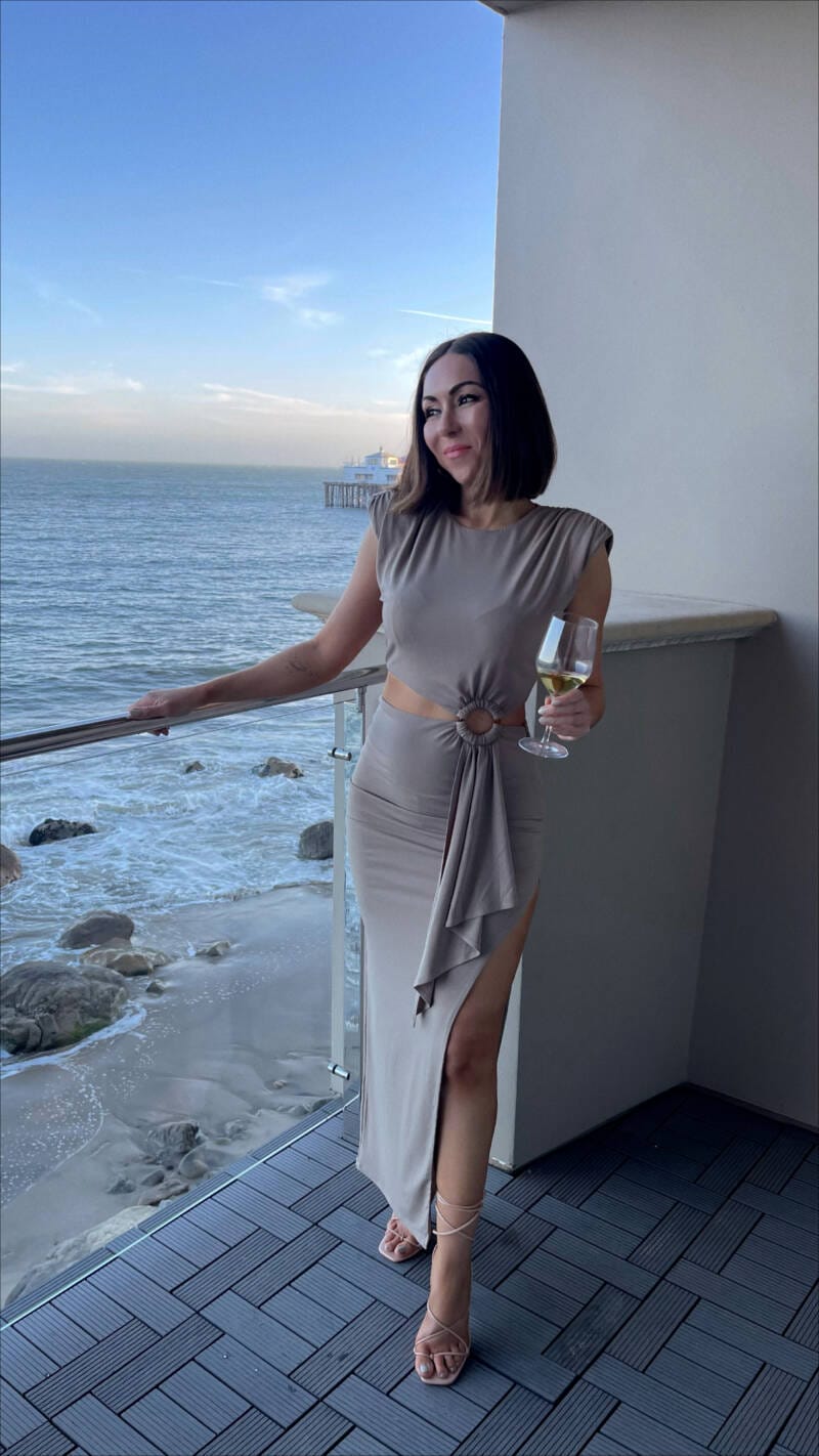 Travel Blogger Nihan drinking wine Malibu Beach Inn overlooking the ocean